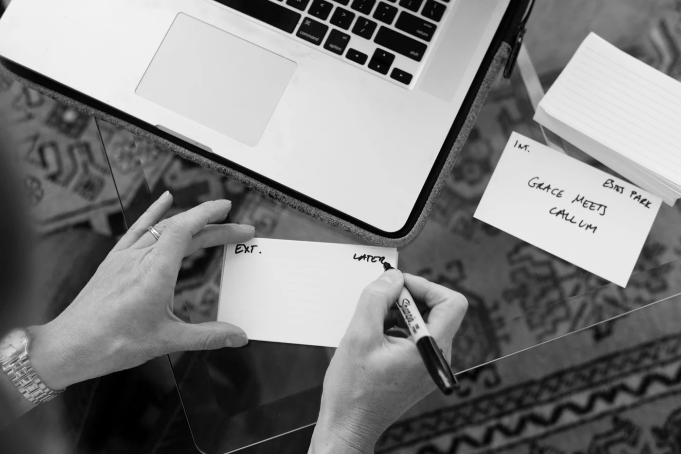 Diane writing a screenplay scene on an index card beside a laptop and other scene cards